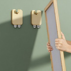 Two wooden wall hooks on a green wall with a person holding a framed picture.