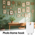 Decorative wall with framed botanical prints and hanging macrame decor, featuring a photo frame hook.