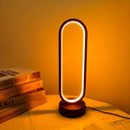 Modern table lamp with warm glow on a surface with books