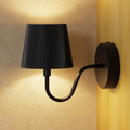 Black wall lamp with pleated shade on a textured wall