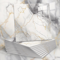 Stack of marble-patterned notebooks with gold accents on a marble surface.